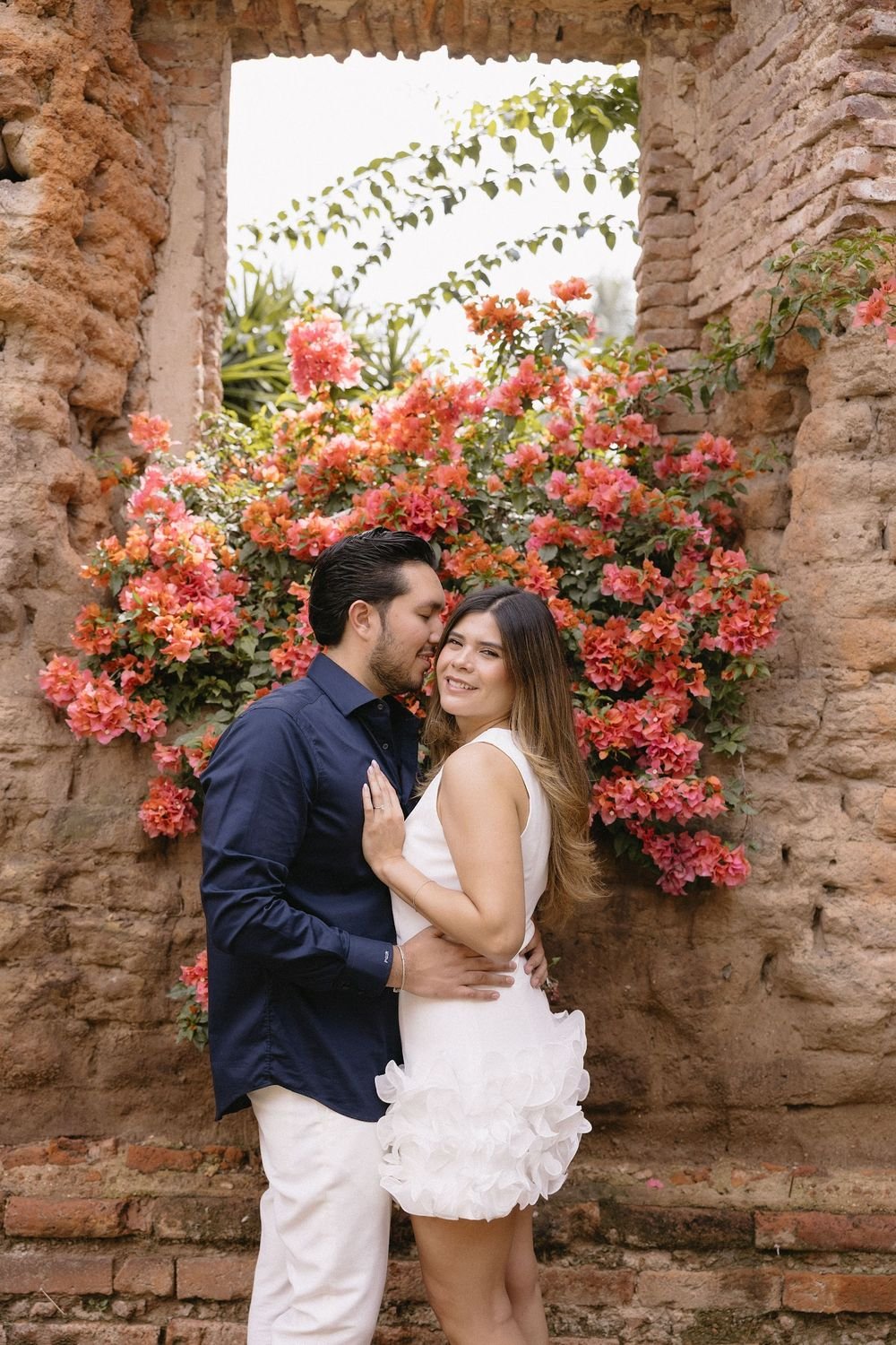 Ivette y Pablo abrazados frente a una bugambilia